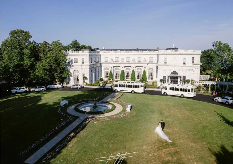 Bride and groom walking on the front lawn during their Rosecliff Mansion wedding.