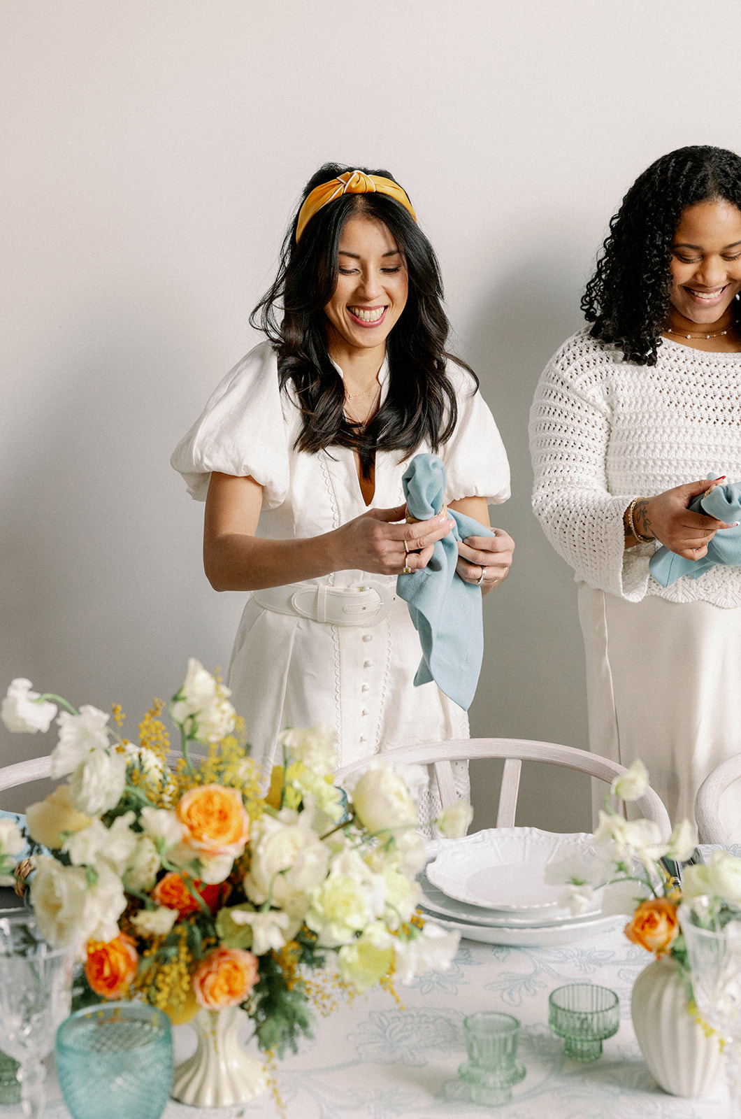Wedding planner and assistant decorate tablescape for styled shoot wedding photos of table.