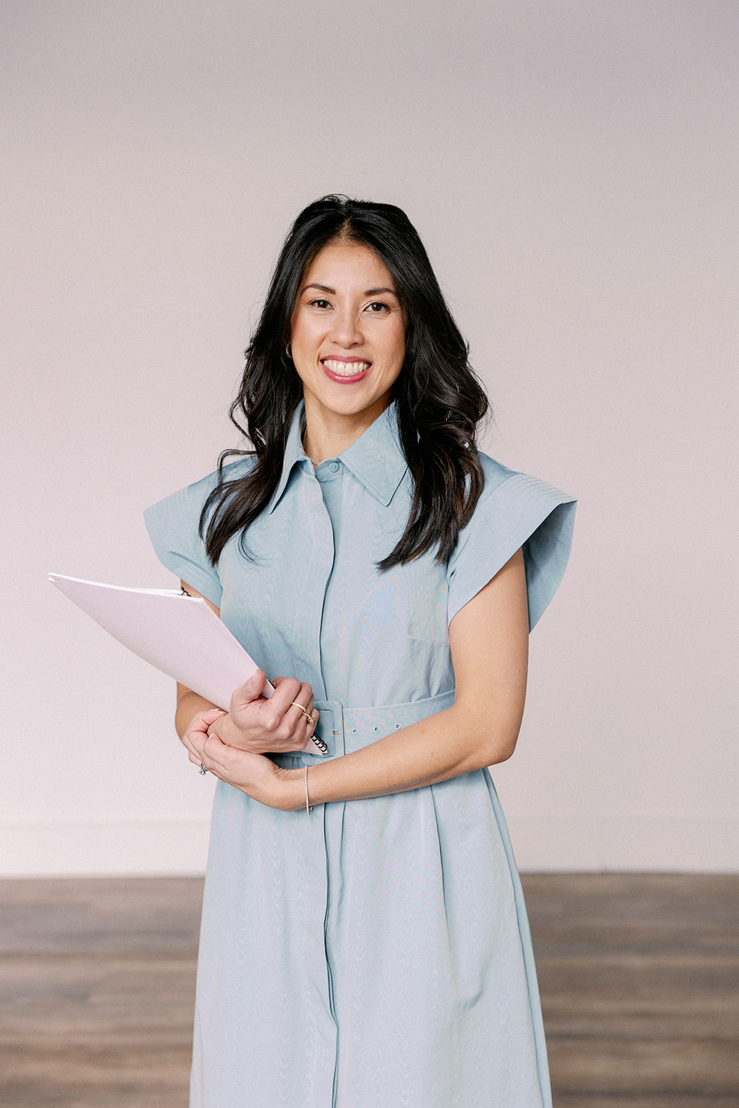 Desiree Adams from Verve Event Co. stands with clip board as she poses for headshot.