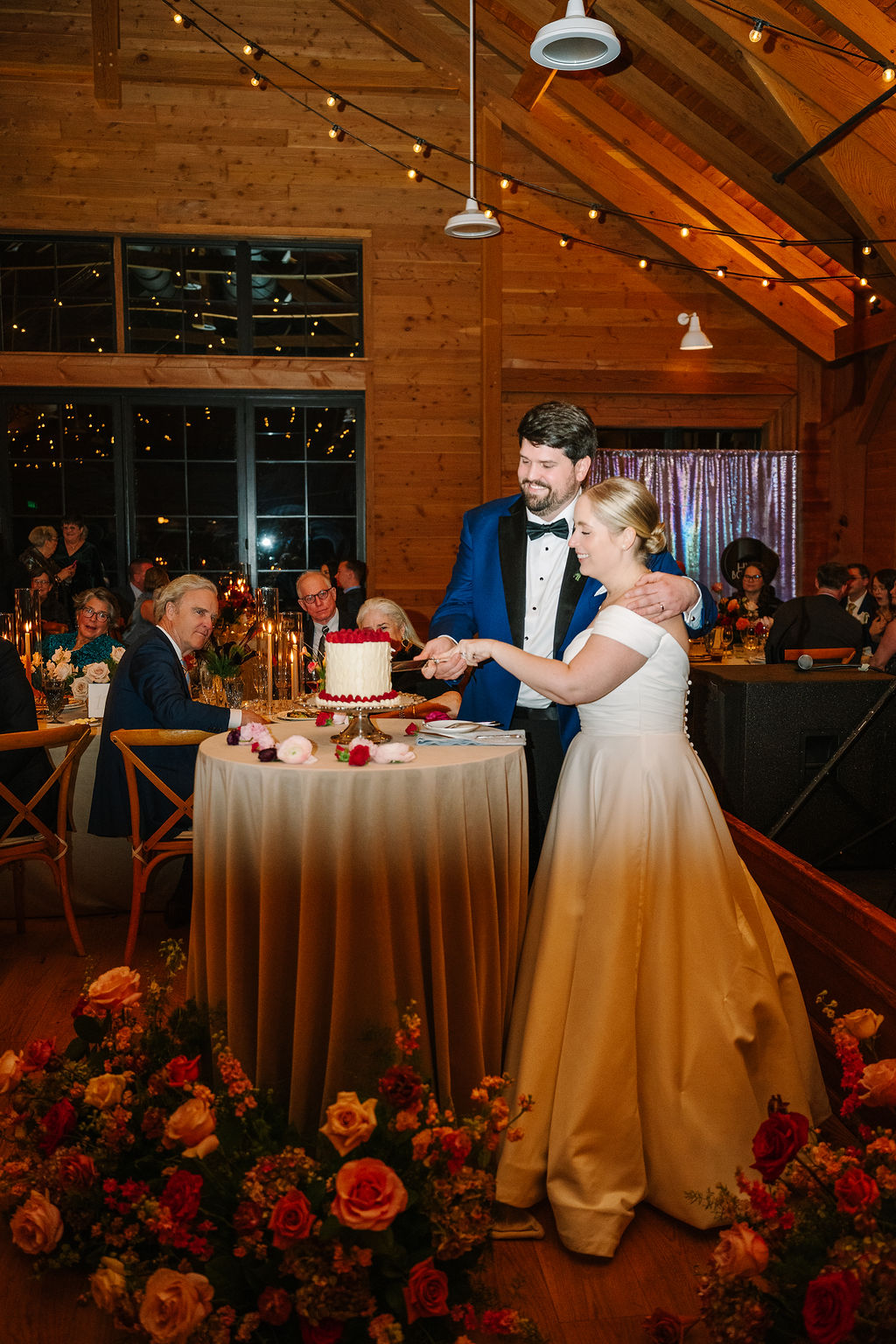 Bride and groom cut into cake together as they stand in their Mid-Atlantic wedding venues space that overlooks the ocean.