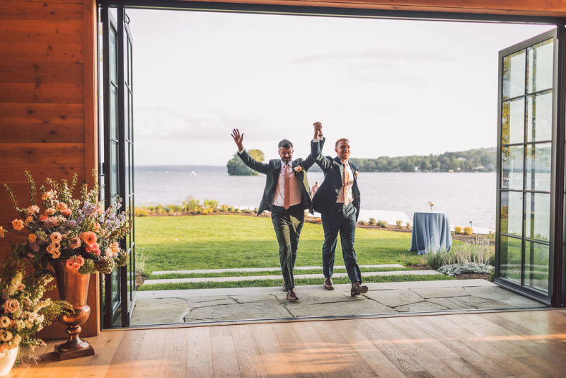 two grooms entering their wedding reception at the Lake House