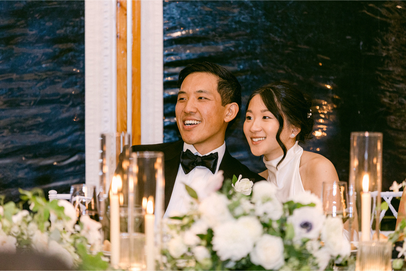 bride and groom smile at speeches