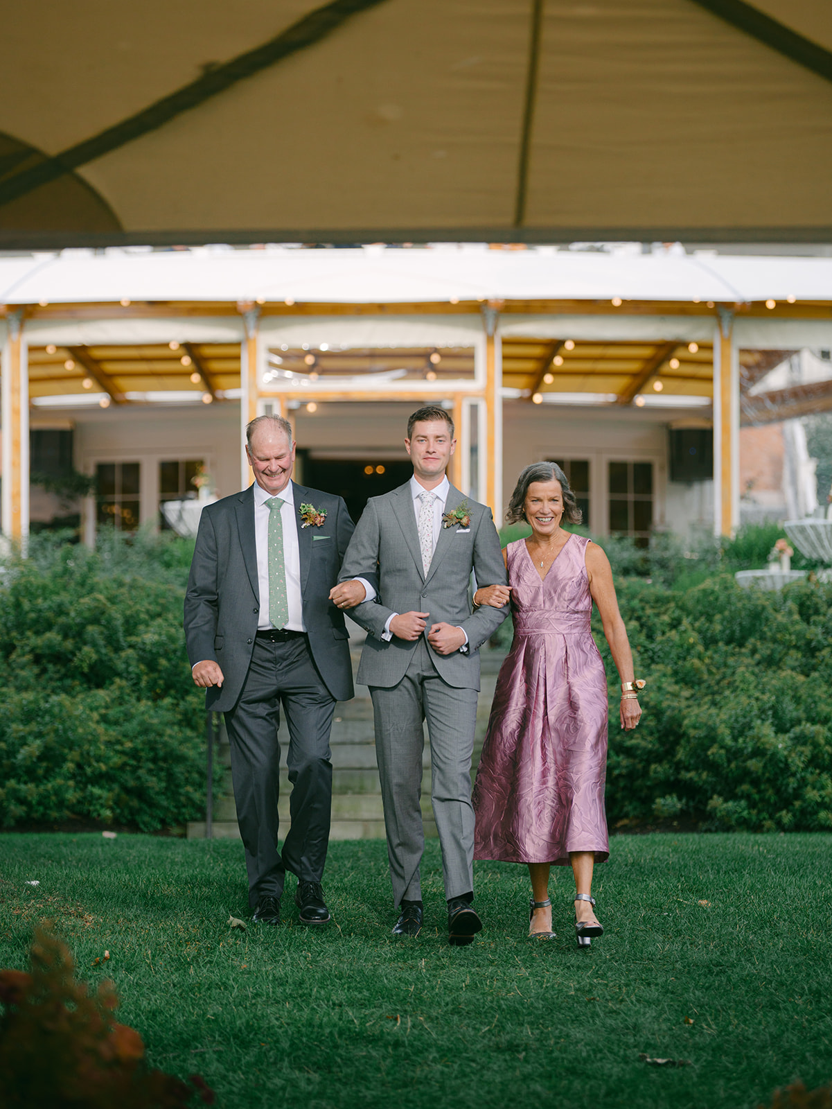 Groom walks with his mother and father down the aisle.