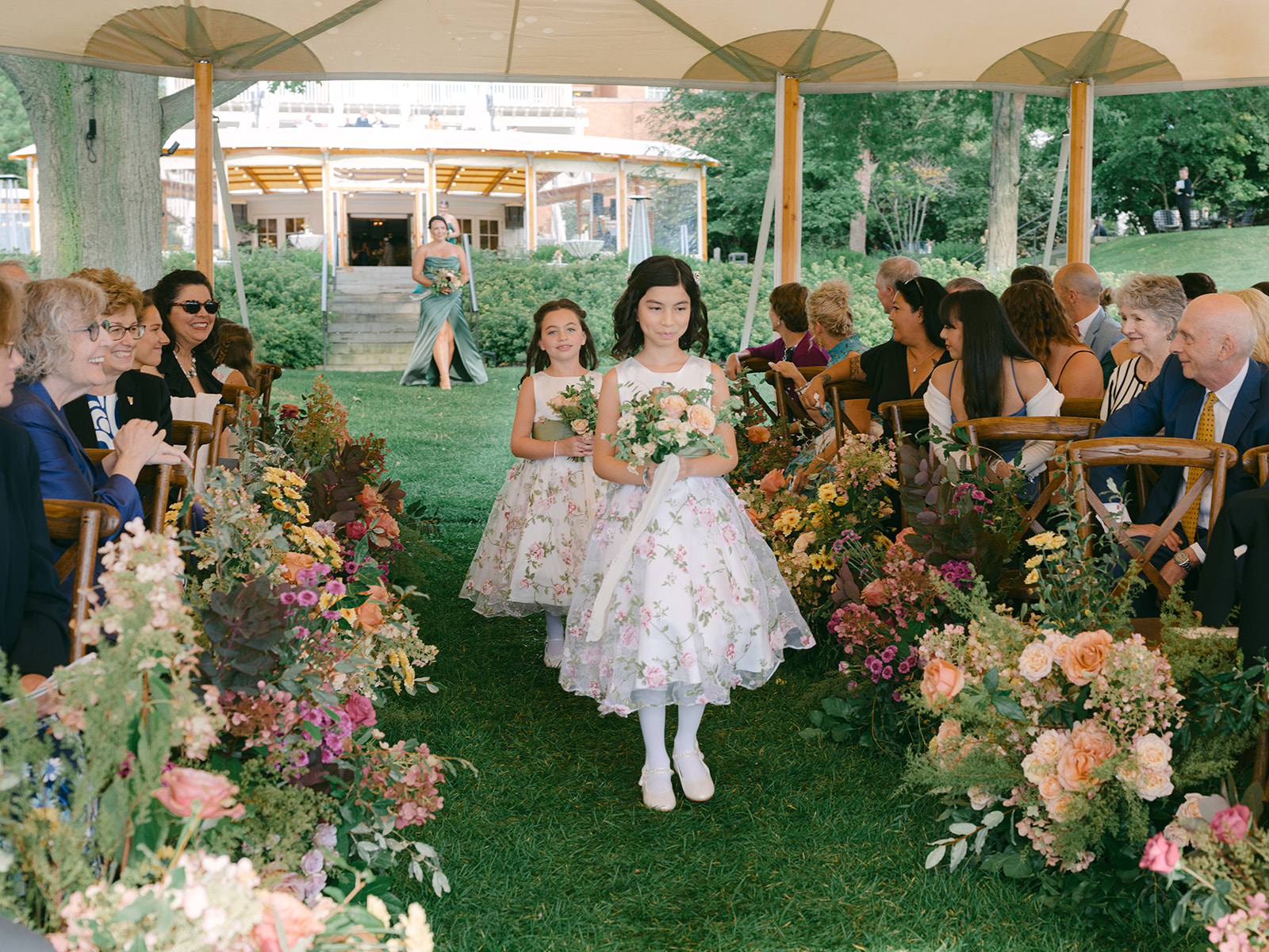 Flower girls walk down aisle during ceremony at Inns of Aurora.