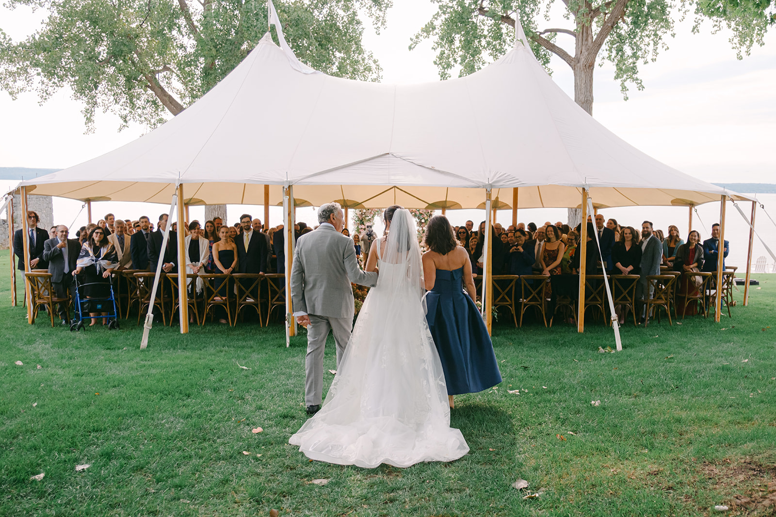 Mother and father walk their daughter down the aisle, surrounded by a beautiful fall wedding design.