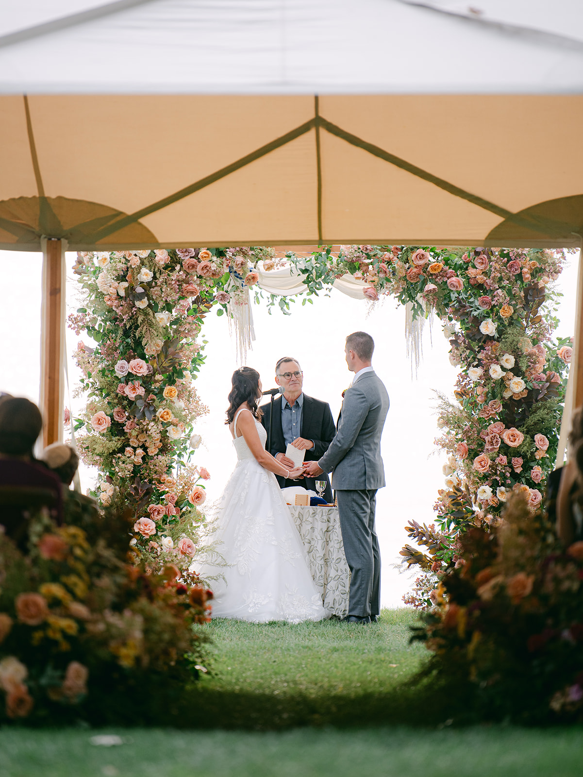Bride and groom stand together holding hands during wedding ceremony at Inns of Aurora.