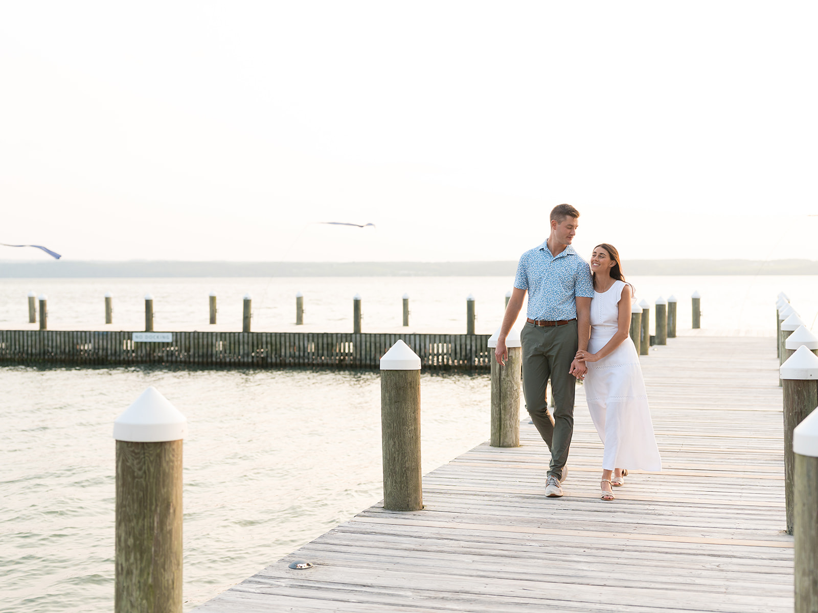Bride and groom walk hand in hand on the dock of Inns of Aurora headed to their welcome reception.