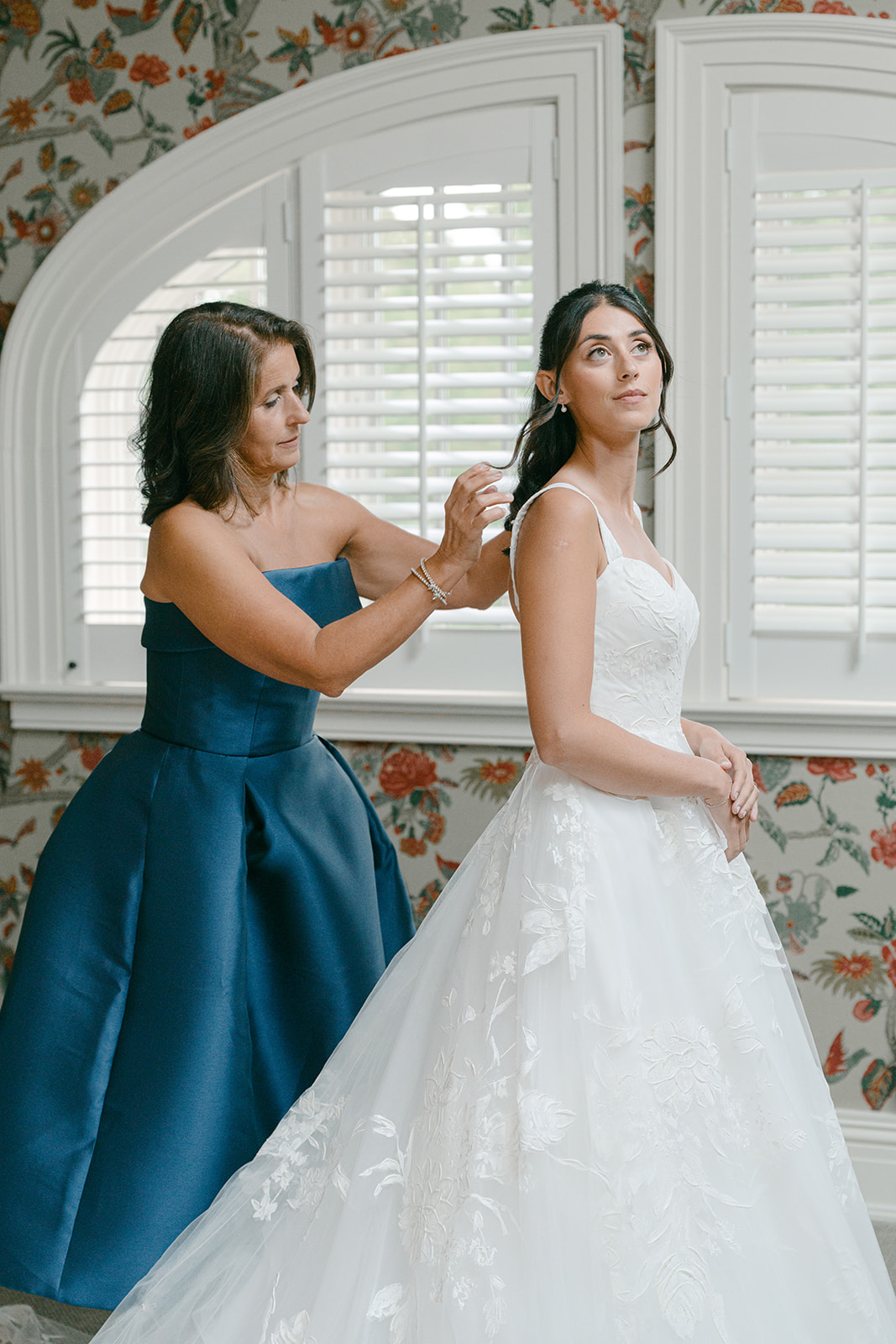 Mother helps bride get into her wedding dress.