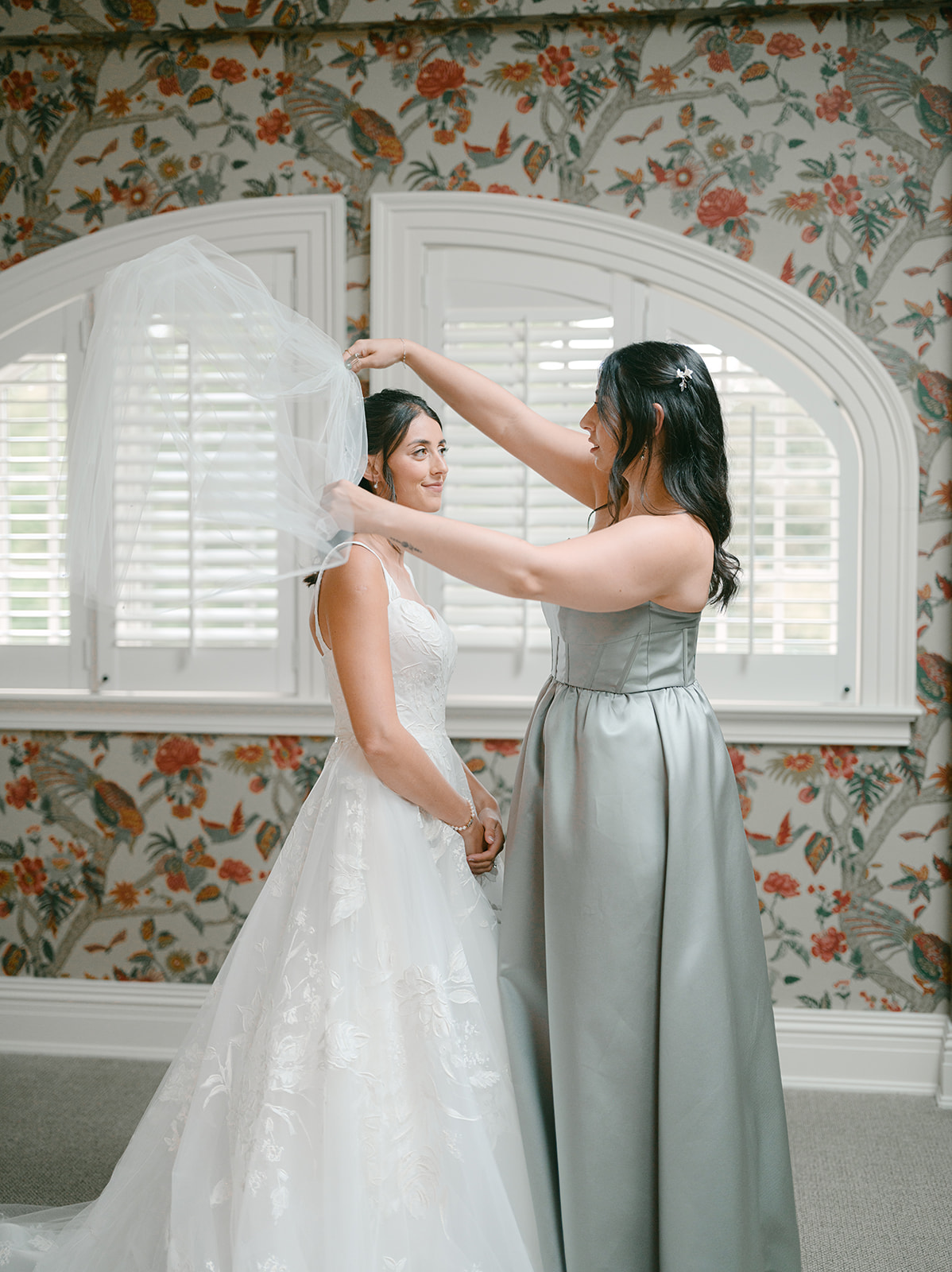 Sister helps put veil on before wedding day.