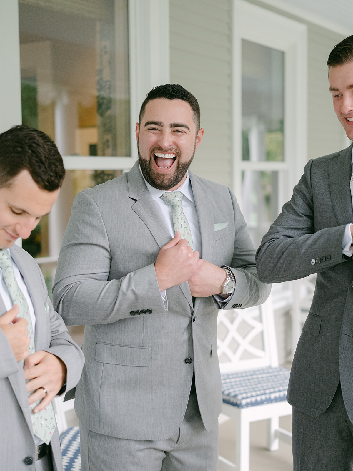 Groomsmen laugh as they are getting ready together for wedding.