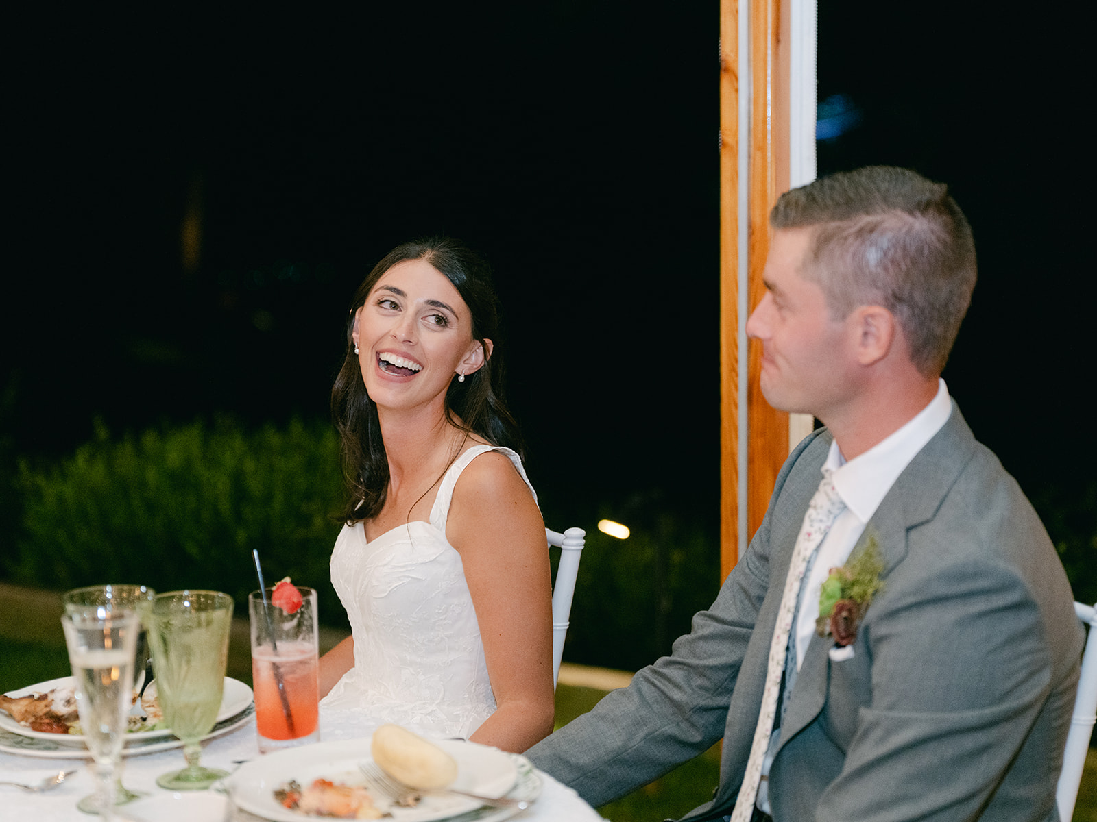 Bride and groom laugh as their sister shares a speech.