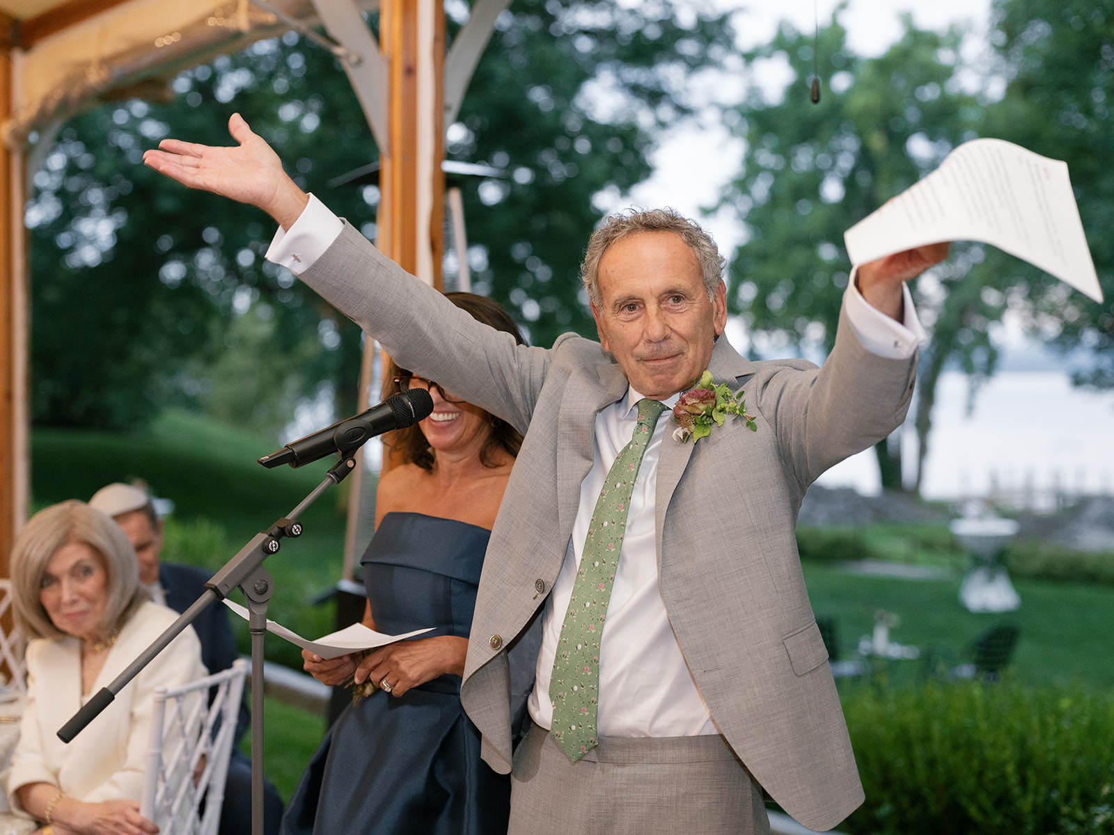 Father of the bride gestures for guests to applaud for the happy couple.