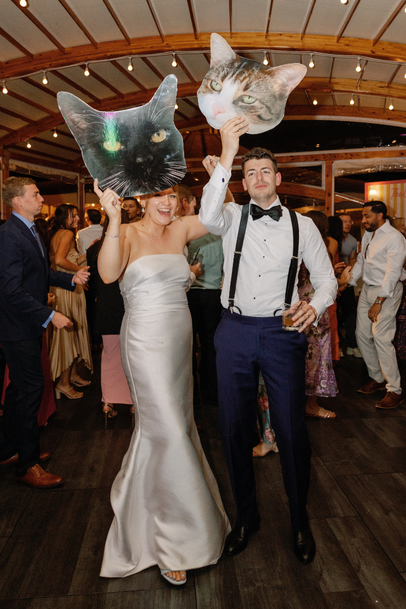 Bride and groom holding up large custom cardboard heads of their cats.