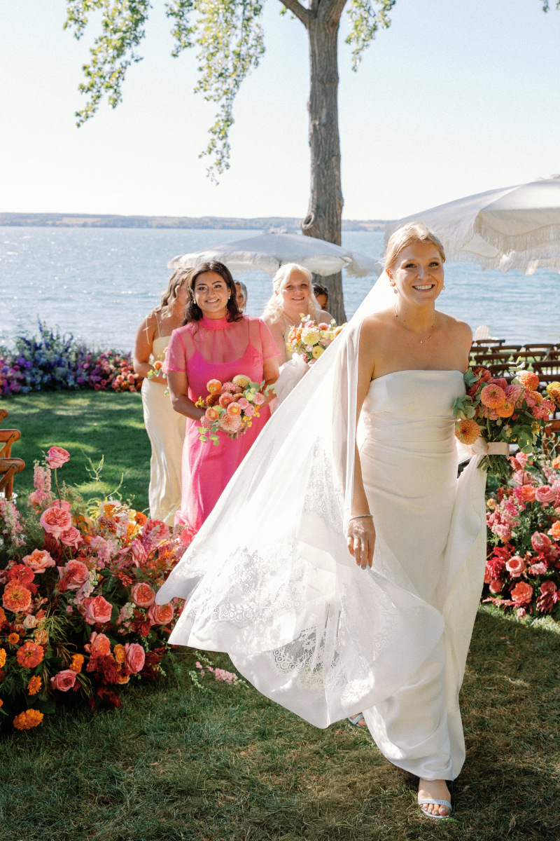 Bride and bridesmaids walk in straight line down the center of the aisle for portraits.