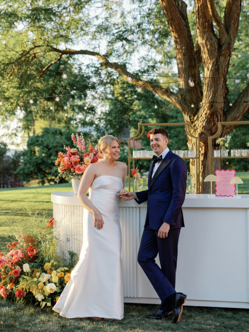 Bride and groom stand in front of bar front sipping signature cocktails.