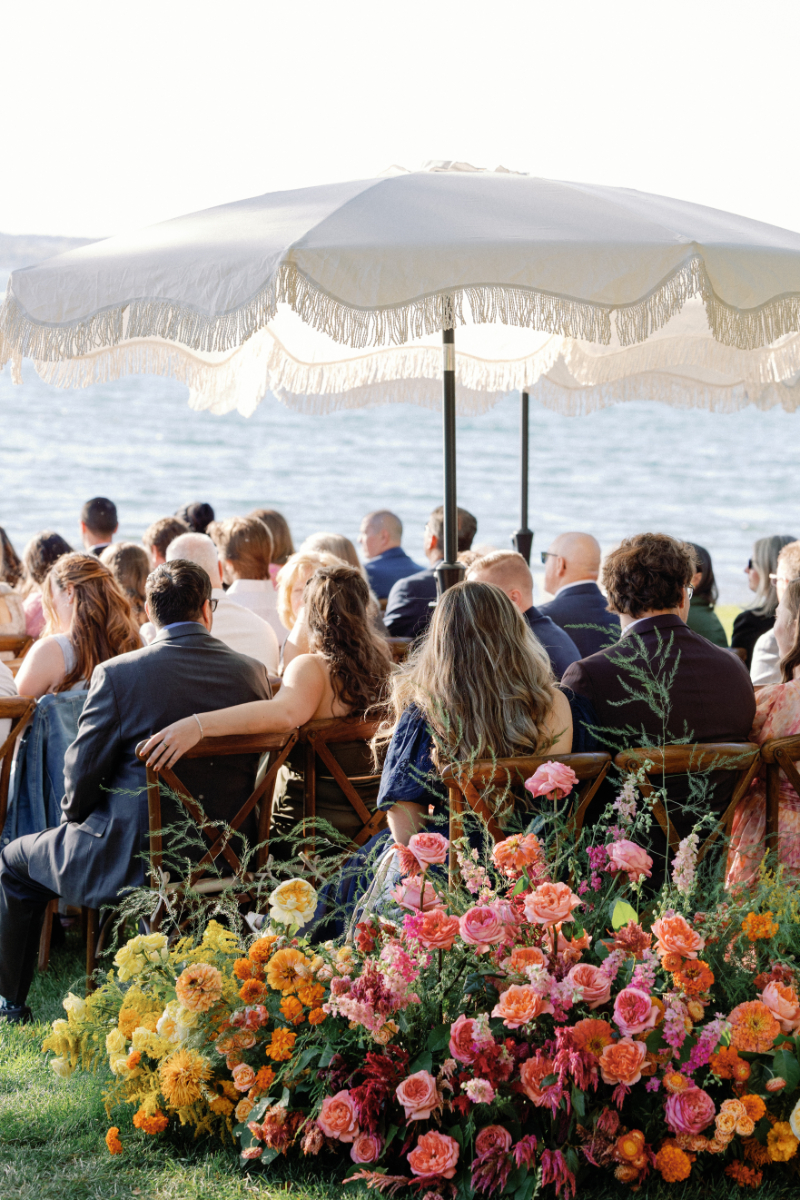Guests sitting under scalloped umbrellas during wedding ceremony.