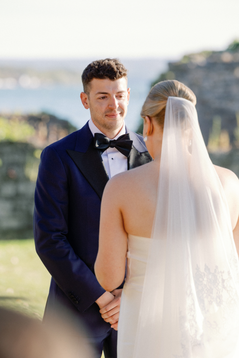 Groom looks at bride, full of tears, as she reads her vows to him.