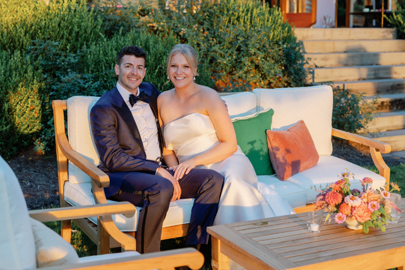 Bride and groom pose for photo as they sit in the lounge seating at cocktail hour.