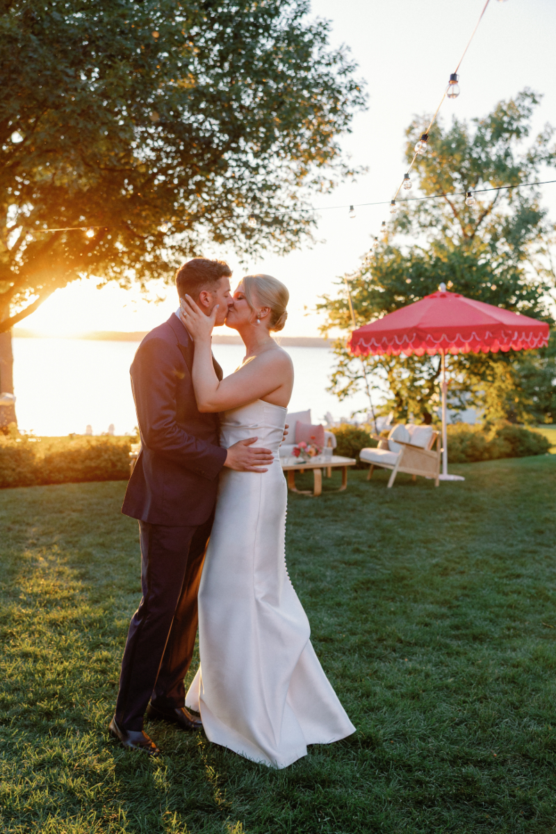 Bride and groom share kiss on the lawn during cocktail hour.