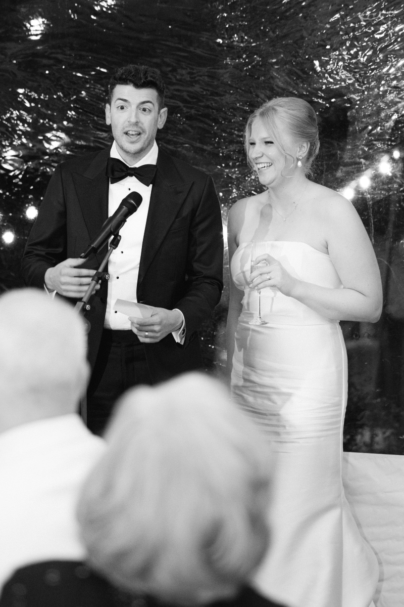 Bride and groom stand to thank guests for attending their wedding.