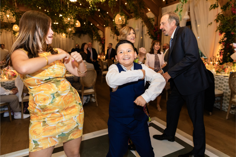 Guests dance on custom monogrammed dance floor at wedding reception.
