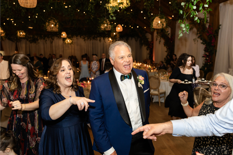 Bride's mother and father dance with guests at wedding reception.