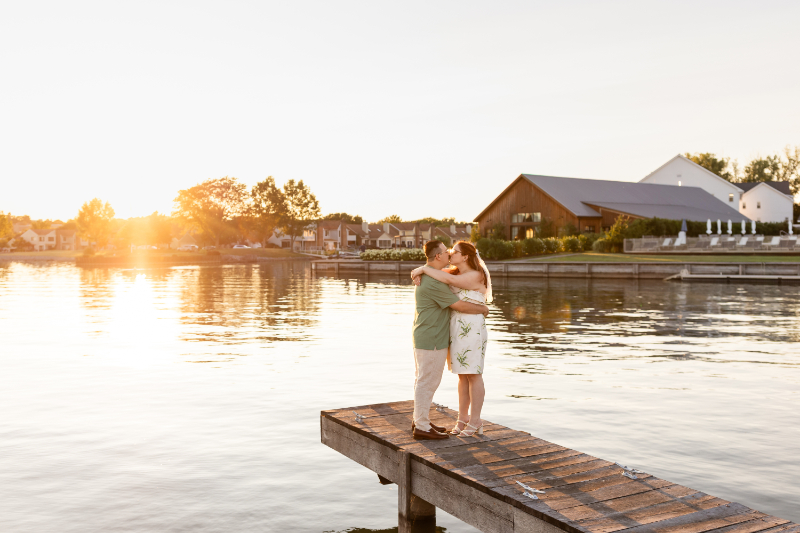 Bride and groom share kiss on the dock of the Lake House on Canandaigua for their summer camp wedding welcome party.