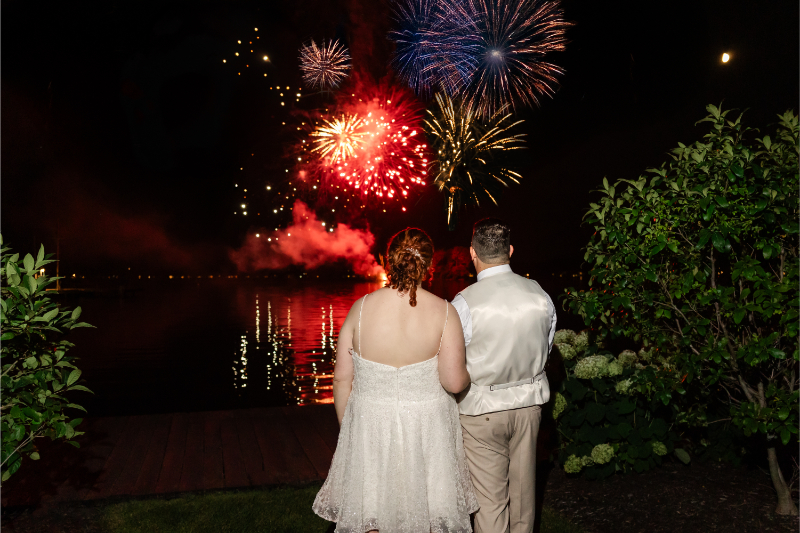 Bride and groom hold hands as they admire a firework display that wrapped up their summer camp wedding at