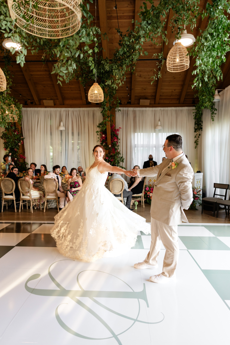 Bride and groom share first dance after make grand entrance to their summer camp wedding reception at The Lake House on Canandaigua.