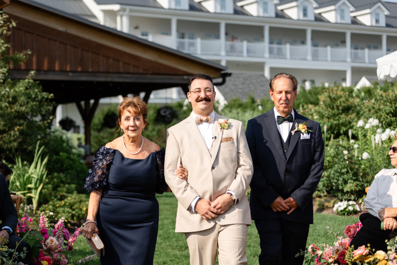 Groom walks down the aisle with his parents.