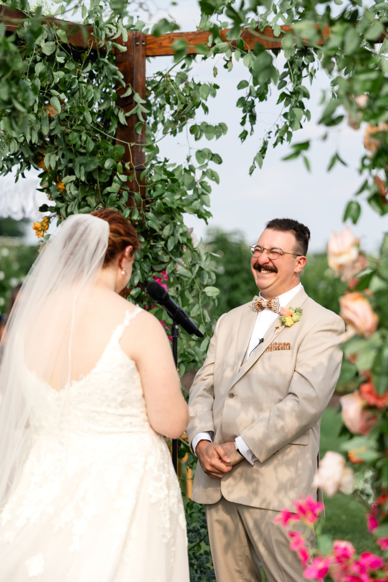 Bride and groom exchange vows under floral filled chuppah at The Lake House on Canandaigua.