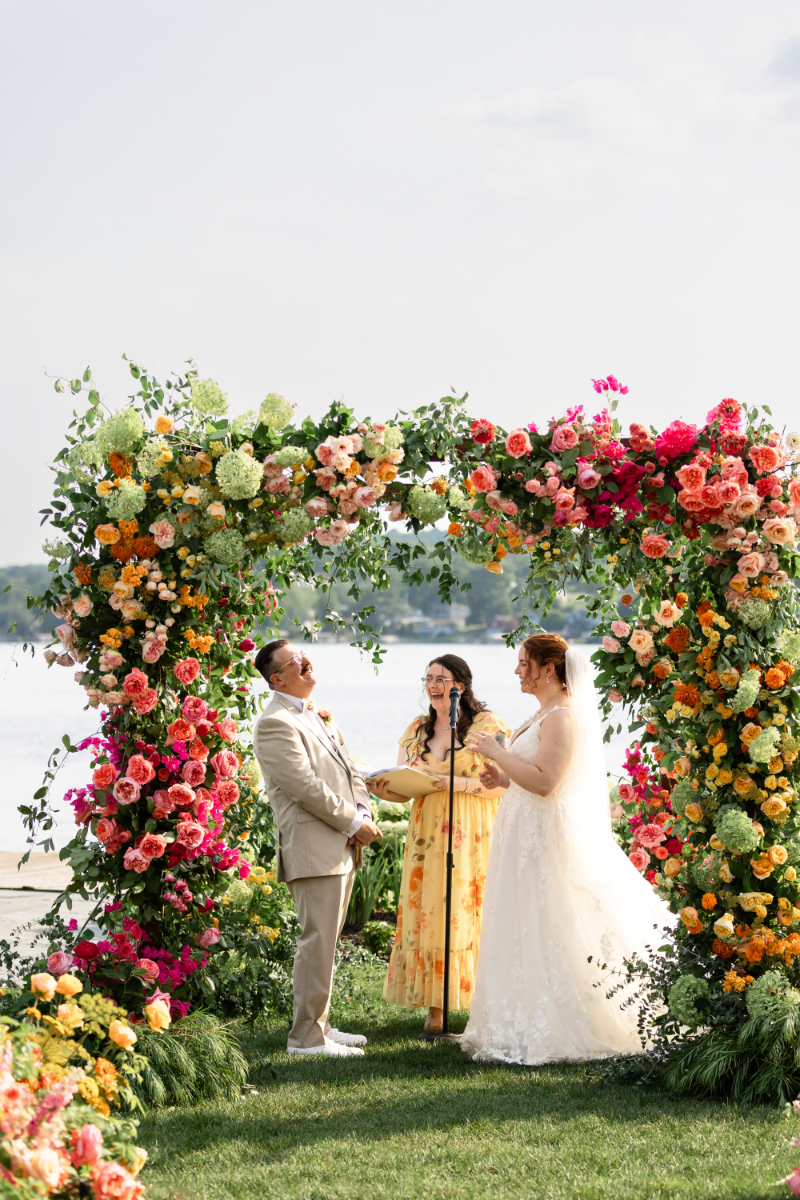 Bride and groom exchange vows under floral filled chuppah at The Lake House on Canandaigua.