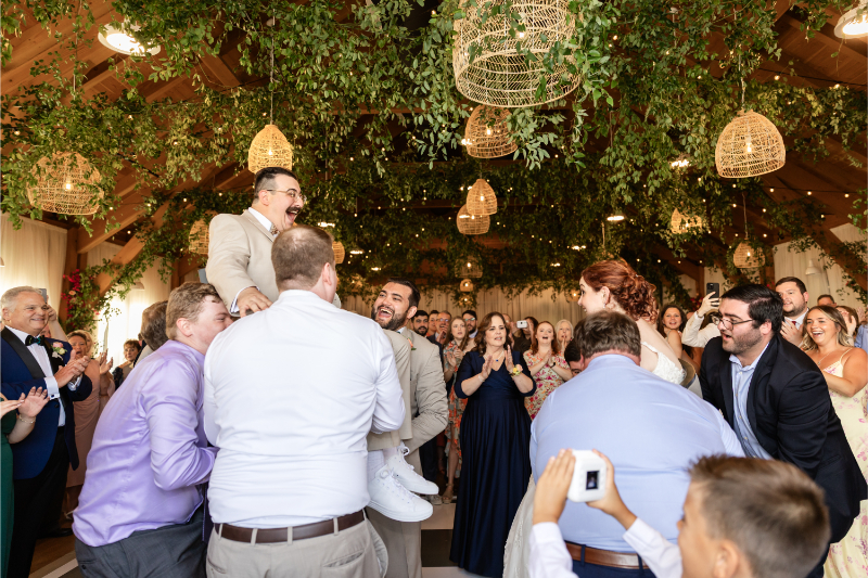 Guests life bride and groom into the air during the Hora.