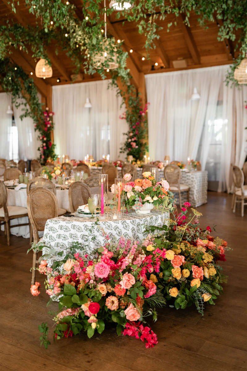 Sweetheart table surrounded by colorful floral arrangement.