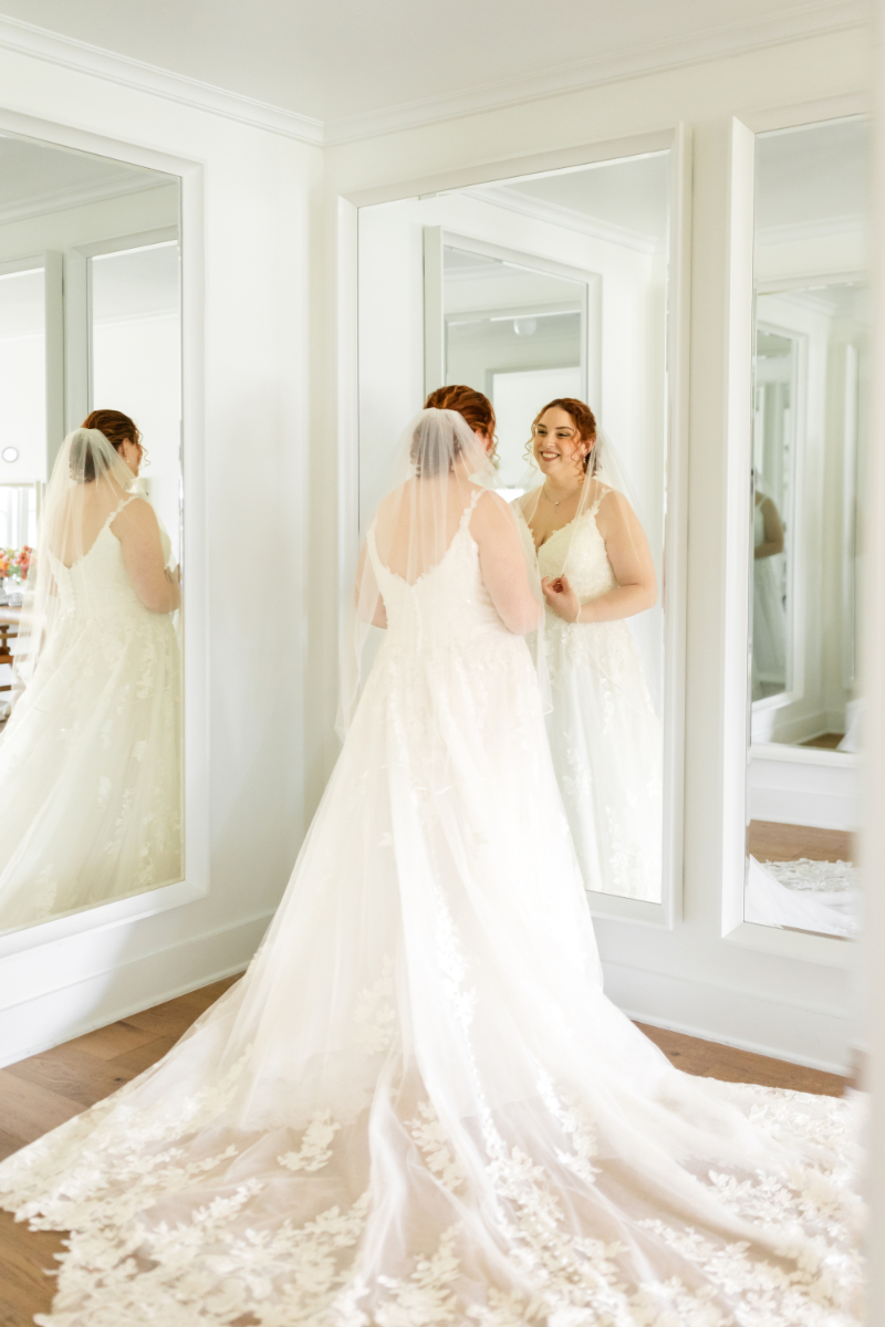 Bride looks into mirror, admiring herself before her summer camp wedding day is in full swing.