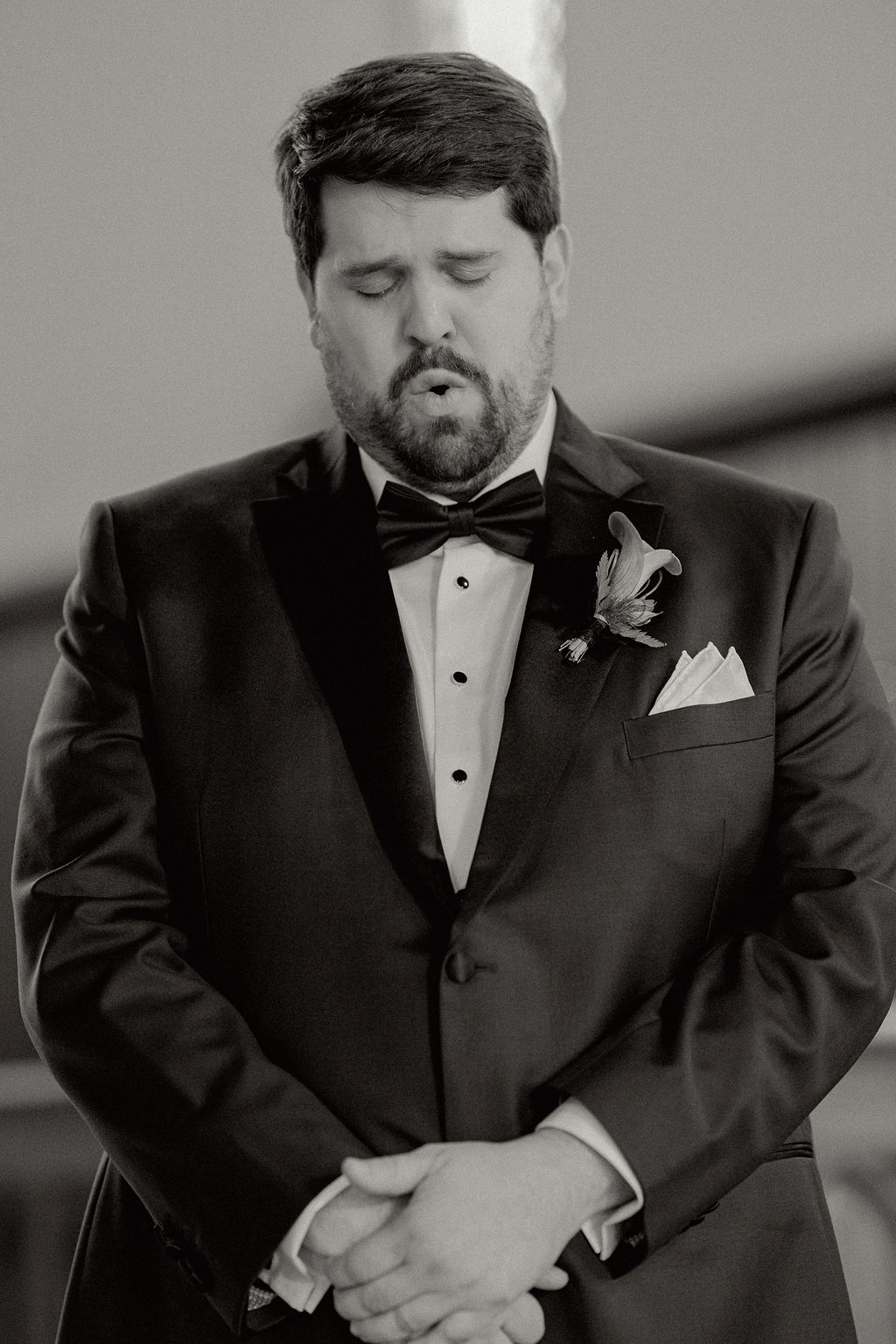 Black and white photo and grooms reaction during wedding ceremony.