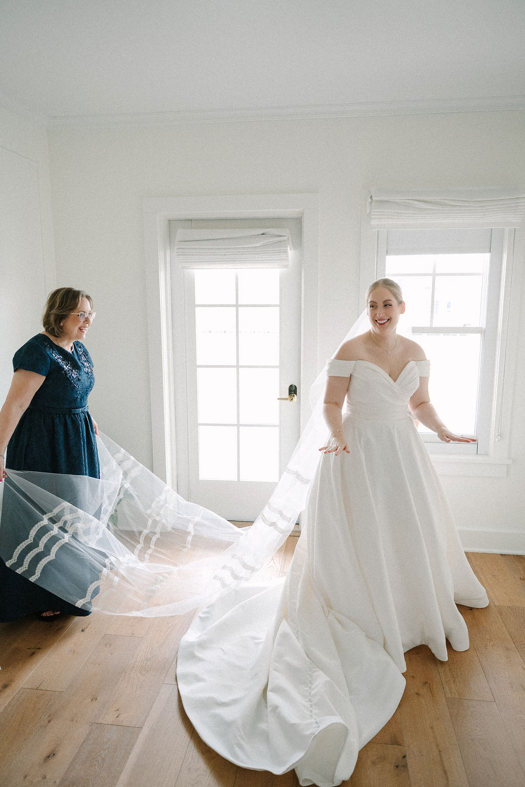 Bride's mother standing behind her, fanning out her veil.