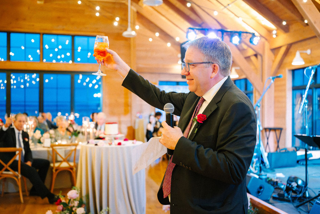Father of the groom raises a glass to toast the newly-weds.
