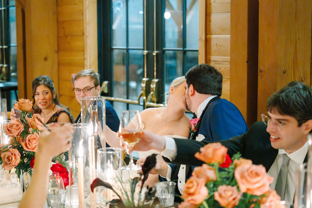 Bride and groom share kiss during their reception dinner.