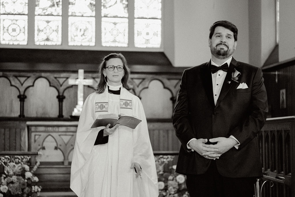 Black and white photo and grooms reaction during wedding ceremony.